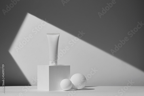 White tube of cosmetics on a white podium with a shadow on the wall