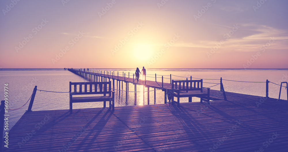 Wooden pier silhouette at sunrise, color toning applied.