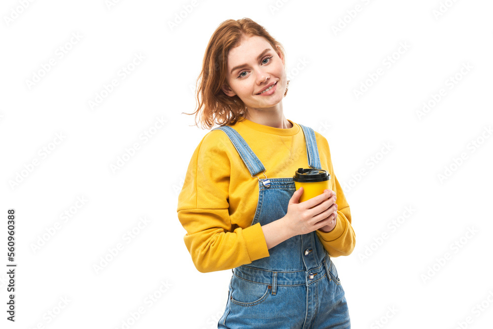 Energetic redhead girl holding and drinking yellow cup of takeaway coffee, smiling and enjoying drink isolated on white background Energetic redhead girl holding and drinking yellow cup of takeaway coffee, smiling and enjoying drink isolated on white background