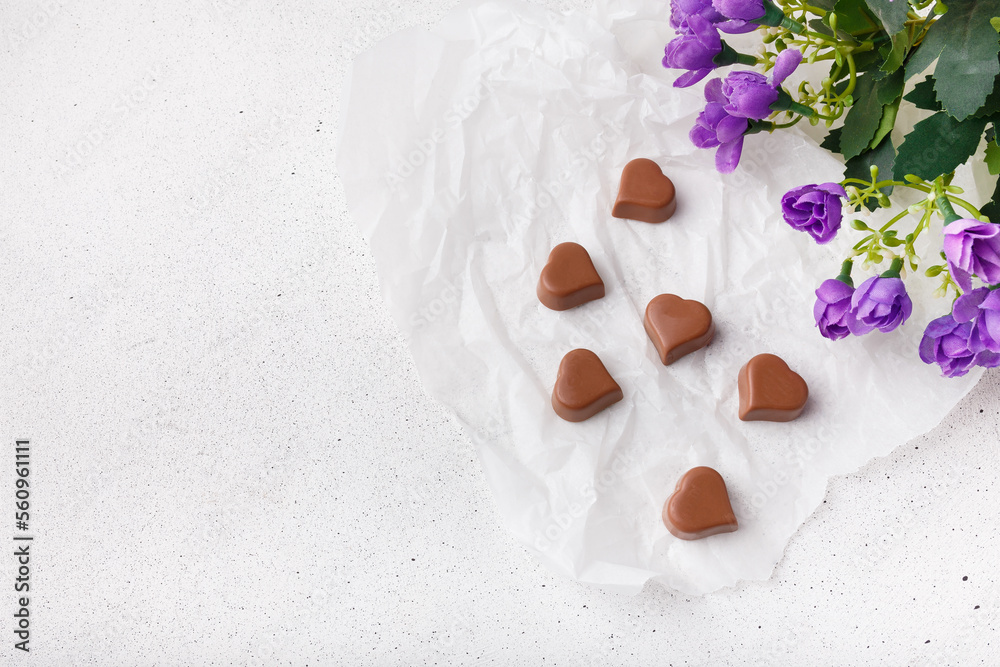 14 February Heart shaped chocolates, violet flowers on white paper background. Valentines day sweets. Copy space 14 February Heart shaped chocolates, violet flowers on white paper background. Valentines day sweets. Copy space