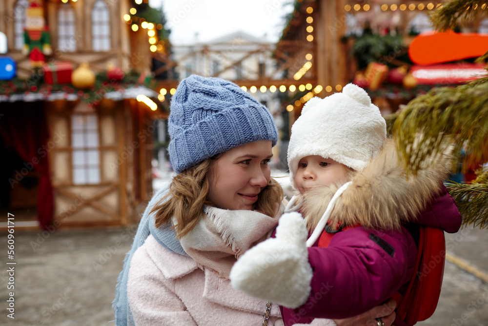 Obraz premium Mother and daughter are walking around the city on Christmas and New Year holidays. Portrait of happy mother and daughter having fun in the street