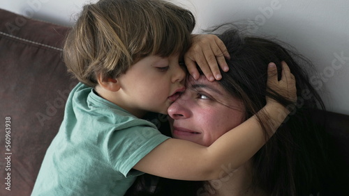 Child embracing mother. Candid little boy hugging mom head. kid covering parent face showing love and affection. Authentic family care