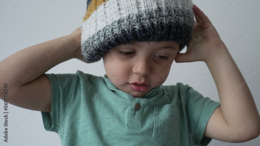 One little boy putting beanie covering face. Funny child wearing wool winter clothing accessory One little boy putting beanie covering face. Funny child wearing wool winter clothing accessory