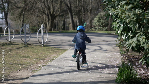 One little boy riding bicycle outdoors at park during autumn season. Kid wearing protective helmet