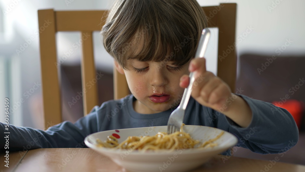 One little boy eating pasta with fork. Child eats lunch meal carb food. Kid nutrition concept