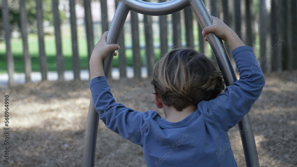 Child spinning at playground spinner structure. One little boy having fun at play space with stainless steel toy Child spinning at playground spinner structure. One little boy having fun at play space with stainless steel toy