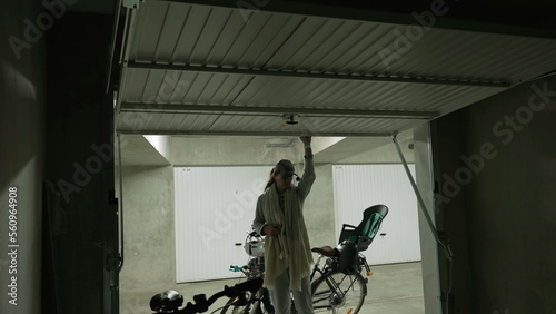 Mother opening storage room in underground parking space. Person opens metal gate interior © Marco