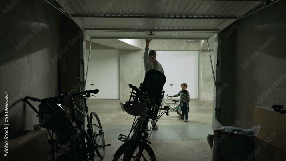 Person opening parking garage door and taking bicycle for a ride. Mother sliding metal gate at storage room takes bike for weekend activity Person opening parking garage door and taking bicycle for a ride. Mother sliding metal gate at storage room takes bike for weekend activity
