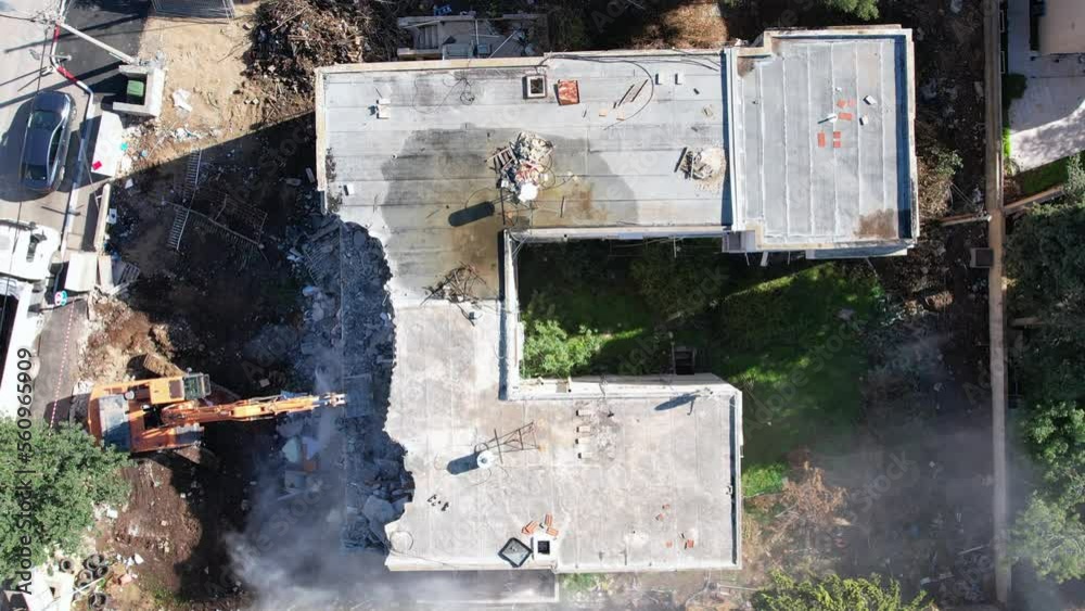 Excavator demolishing barracks for a new construction project. Excavator demolishing barracks for a new construction project.
