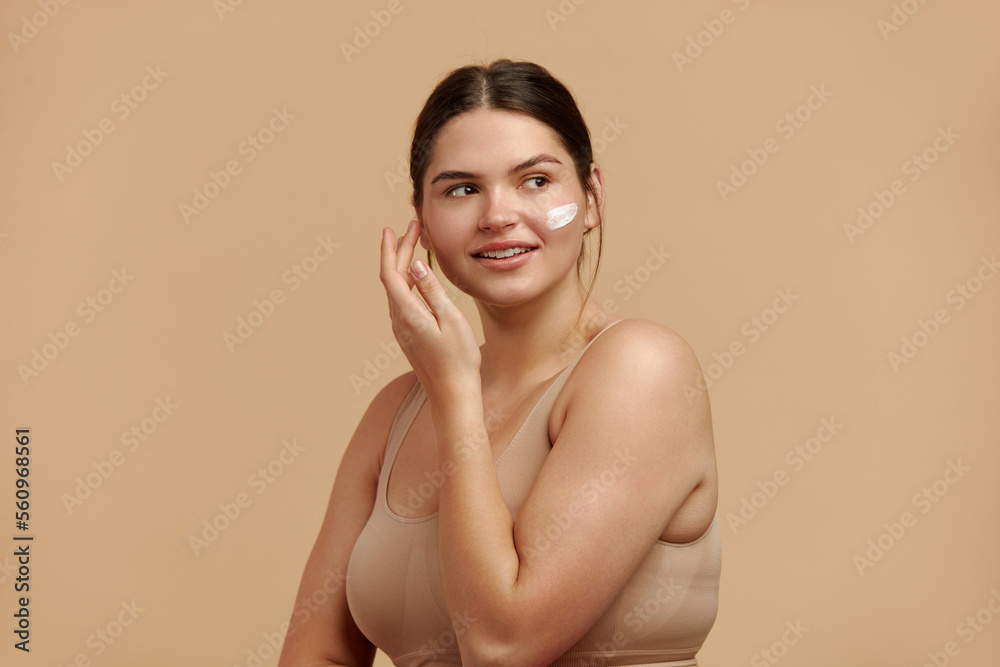 Obraz premium Positive Woman Applying Face Cream. Closeup Of Female Model With Fresh Skin Applying Cosmetic Product Under Eyes. Skincare Concept. High Resolution 