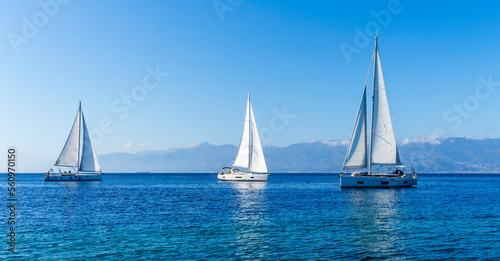 sailing yacht boats with white sails in blue sea , seascape of beautiful ships in sea gulf with mountain coast on background © Yaroslav