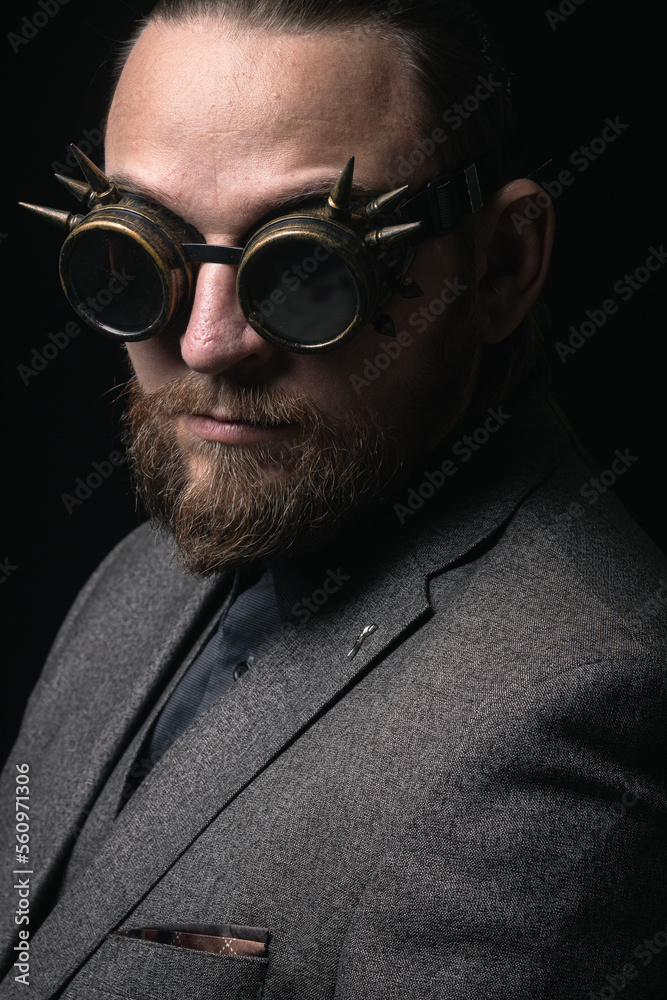 Fototapeta premium charismatic man in a classic suit and steampunk goggles on a black background stylish Portrait