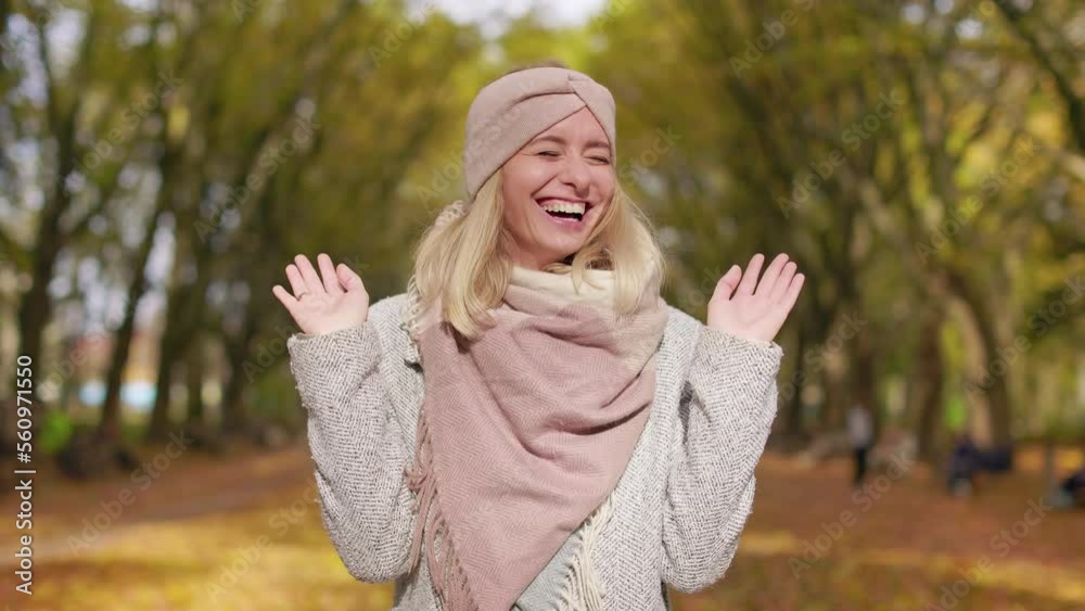 Front view of smiling, blonde girl standing in park, joking. Beautiful, young lady looking at camera, laughing, enjoying autumn. Concept of happiness and sincere emotions. Front view of smiling, blonde girl standing in park, joking. Beautiful, young lady looking at camera, laughing, enjoying autumn. Concept of happiness and sincere emotions.