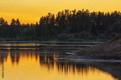 The yellow-orange sunset is reflected in the lake in the evening.
