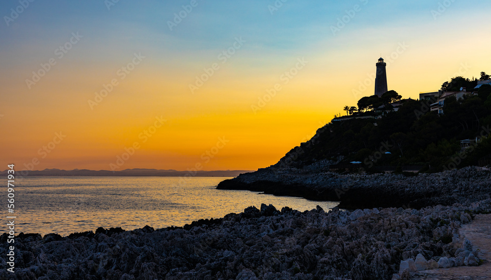 Sunset evening landscape of southern rocky shore of Cap Ferrat cape at French Riviera of Mediterranean Sea with Le Phare Lighthouse in Saint Jean Cap Ferrat town in France