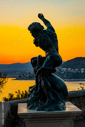 Poseidon Le statue aside Phare Lighthouse at southern rocky shore of Cap Ferrat cape at French Riviera of Mediterranean Sea in Saint Jean Cap Ferrat in France