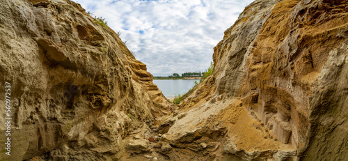 A canyon of sand on the shore of a lake in the mountains.