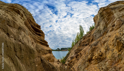 A canyon of sand on the shore of a lake in the mountains.
