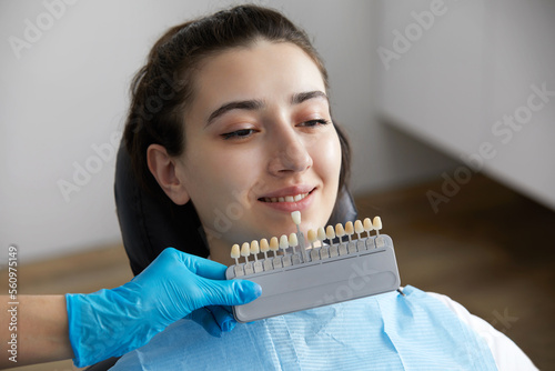 Dentist choosing color tone of tooth enamel for patient. Dentist applying sample from tooth enamel scale