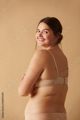 Full Figured Woman. Happy Curvy Oversize Woman Posing In Beige Lingerie At Studio. Confident Plus Size Lady Smiling Indoors. Body Imperfection, Body Acceptance, Body Positive And Diversity Concept 