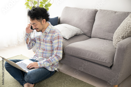 Asian man talking on phone while working on computer in room Copy space available on right