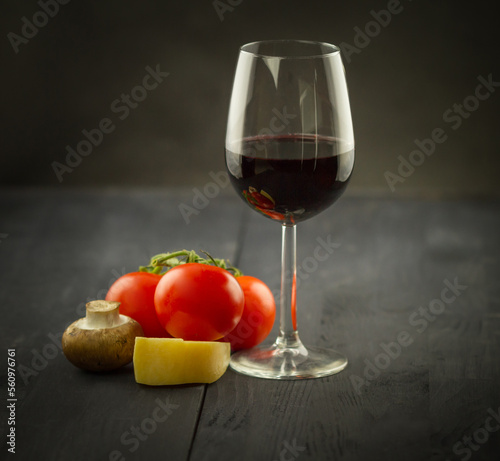 Glass of red wine with cheese and tomatoes on a wooden table