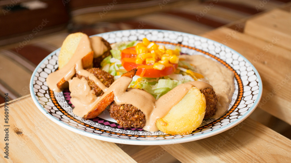 Falafel combo dish with vegetables. Faláfel or falafel​ is a chickpea or broad bean croquette. It is usually consumed in the Middle East.