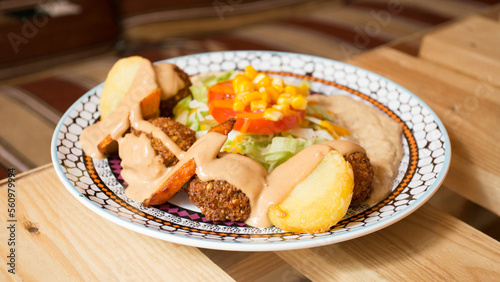 Falafel combo dish with vegetables. Faláfel or falafel​ is a chickpea or broad bean croquette. It is usually consumed in the Middle East.