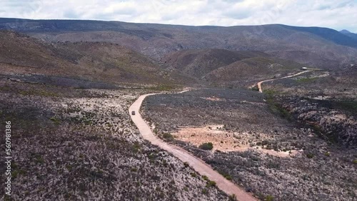 Tracking Shot flying forward turning right over a  a curvy dirt road at a dessert valley in Cloetesberg,  on edge of the klein karoo semi desert region and garden routes, Western Cape, South Africa. photo
