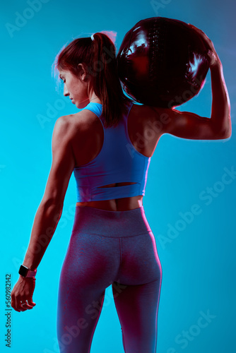 Back view of a sportswoman doing exercises with medicine ball. Long exposure movement.