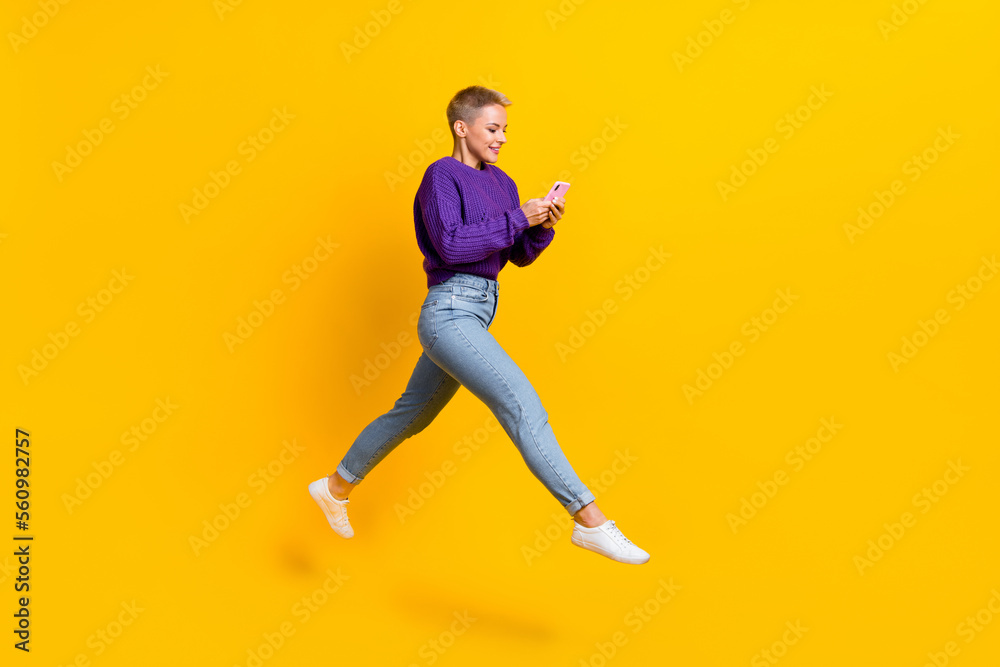 Full length profile photo of active excited person run jump use telephone isolated on yellow color background
