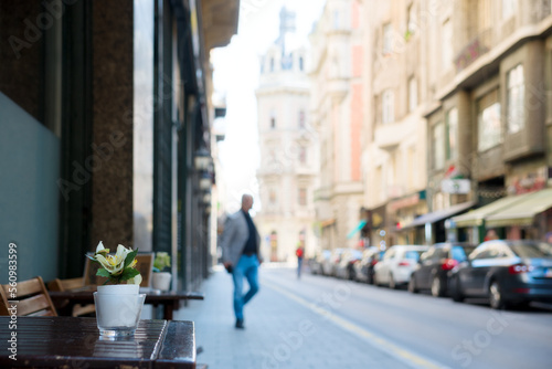 Flowers on a street cafe table, person walking