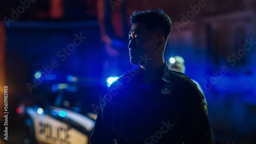 Close Up Shot: Portrait of a Young Asian Male Police Officer Looking Away Firmly Under Siren Lights. Heroic Officer of the Law on Duty, Keeping Citizens and Civilians Safe, Fighting Crime