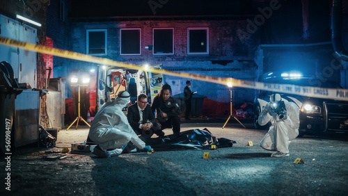 Team of First Responders Arriving at a Murder Scene in a Back Alley. Police Officer and Detective Making Preliminary Assumptions of the Potential Events of the Night and Consider the Evidence and Body