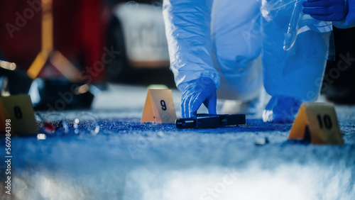 Forensics Working on Crime Scene at Night Gathering Evidence. Police Specialists Packing the Criminal's Gun After Case of Gang Violence. Violent Incident of Mass Shooting and Homicide