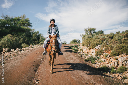 Young woman riding a horse with the picturesque landscape on the background. © polinaloves
