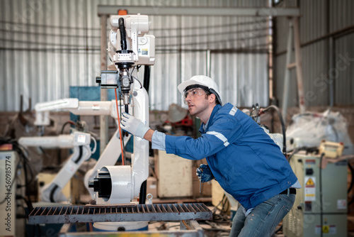 Engineer factory industry wearing safety uniform work and checking system of the welding robots for welding steel electrical control system is robot automate for industry manufacture concept. © APchanel