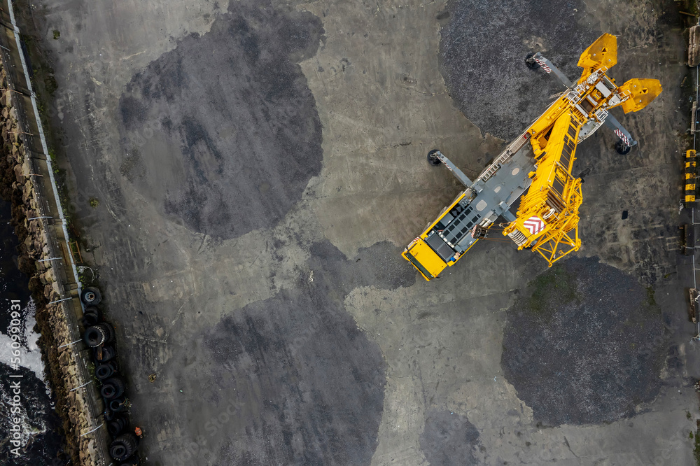 Tall yellow color track crane in a yard. Heavy machinery industry. Aerial view. Tall yellow color track crane in a yard. Heavy machinery industry. Aerial view.