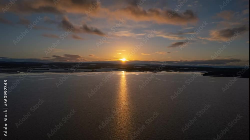 Aerial timelapse shot at sunset over a lake with a snow-covered shore Aerial timelapse shot at sunset over a lake with a snow-covered shore