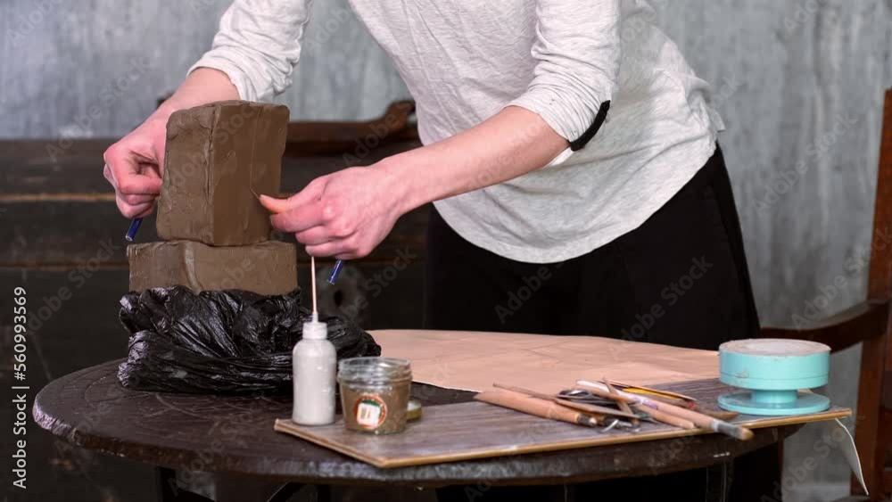 Woman sitting by table, kneading clay and making earthenware at lesson Woman sitting by table, kneading clay and making earthenware at lesson