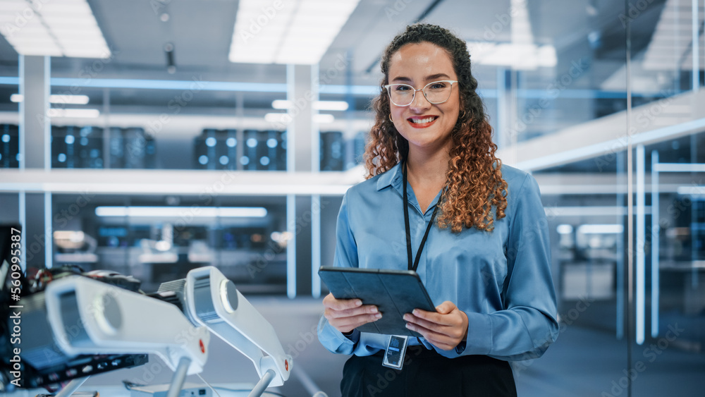 © Gorodenkoff - Portrait of a Beautiful Hispanic Female Wearing Glasses, Using Tablet Computer, Looking at Camera and Smiling. Businesswoman, Information Technology Manager, Robotics Engineering Specialist.
