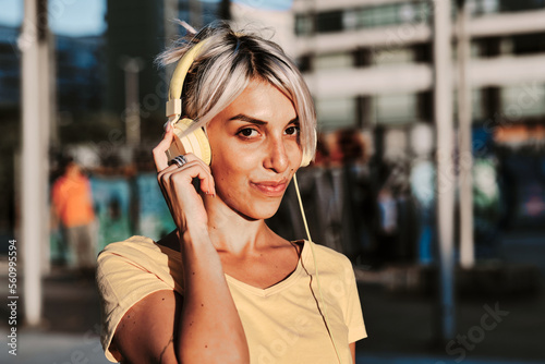 Woman looking at the camera while listening to music with headphones.