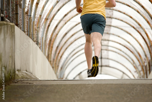 An athletic male jogging through a pedestrain overpass. photo