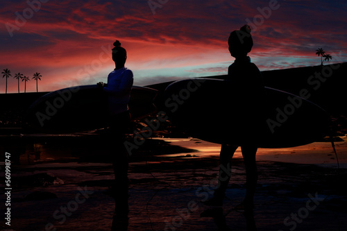 Two young girls ready to surf at sunset on Canary islands photo