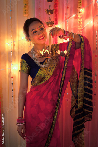 Beautiful Indian woman smiling while holding hanging diya lamps - Diwali Festival. Beautiful Indian woman smiling while holding diya oil lamps on diwali festival photo