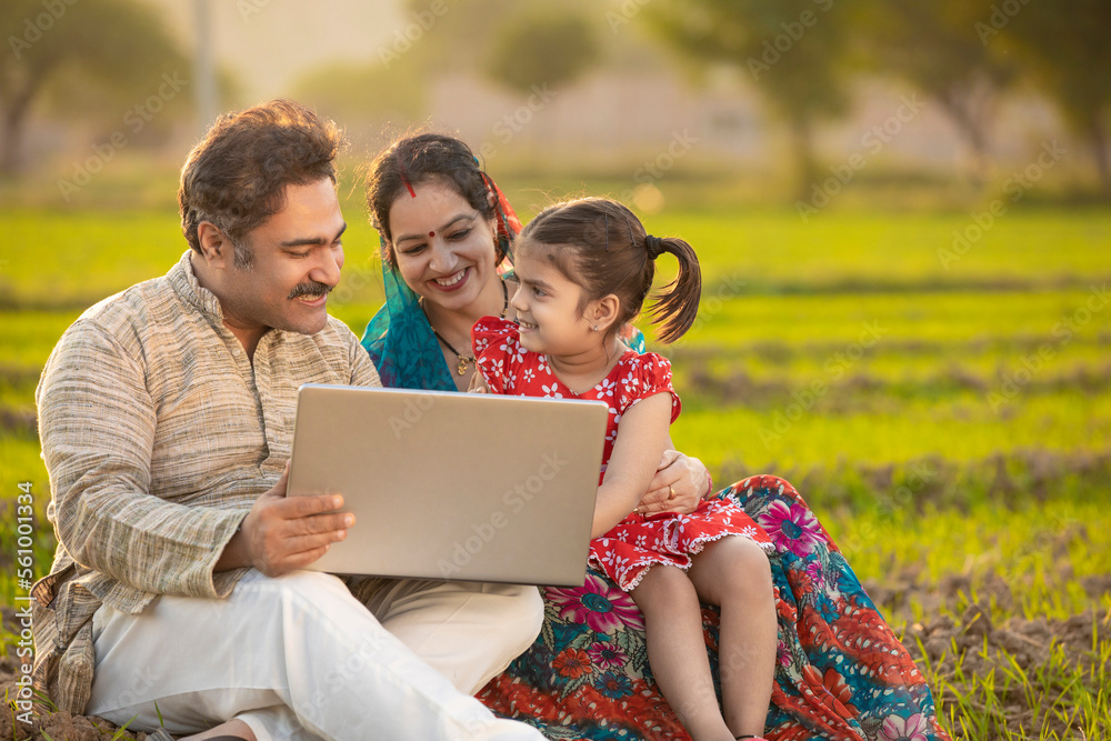 Indian farmer using laptop with wife and daughter at agriculture field. Indian farmer using laptop with wife and daughter at agriculture field.