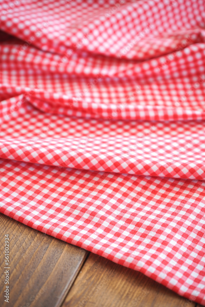 Fold pink plaid fabric or tablecloth on wood desk with selective focus Fold pink plaid fabric or tablecloth on wood desk with selective focus