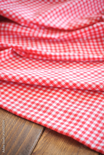 Fold pink plaid fabric or tablecloth on wood desk with selective focus