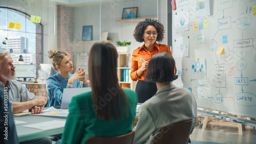 Diverse Modern Office: Successful Black Female Digital Entrepreneur Uses Whiteboard with Big Data, Statistics, Talks about Company Growth, Discusses Strategy with Investors, Top Managers, Executives photo