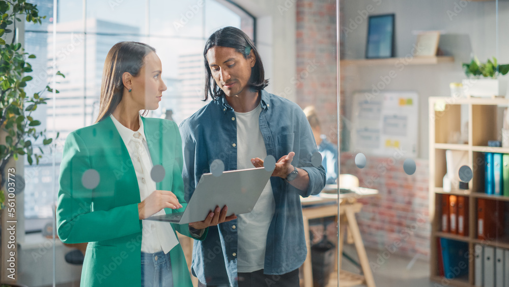 Obraz premium Businesspeople in Modern Office: Business Meeting of Two Managers Using Laptop. Female CEO and Operations Director Talk, Discuss Corporate Strategy, Implementing Marketing and Financial Plans
